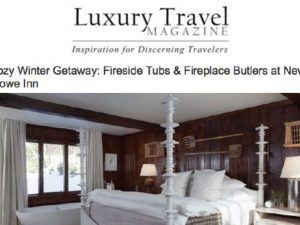 A cozy, rustic bedroom reminiscent of a luxury travel magazine, featuring dark wood walls, a white canopy bed with gray bedding, large windows offering snowy views, and a freestanding bathtub beside the window.