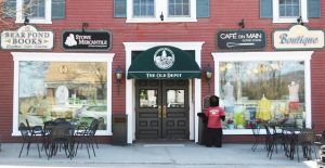 A storefront labeled The Old Depot with three shops—Bear Pond Books, Stowe Mercantile, and Café on Main—stands out on the hot list. Outdoor tables and a bear statue in a red shirt invite you to this red building with green accents.