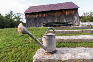 A watering can rests on a stone block, evoking the peaceful simplicity of a Vermont Vacation.