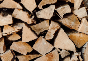 A close-up view of a stack of chopped firewood at Edson Hill - Stowe Vermont Inn, showing rough, uneven surfaces and natural wood grain patterns. The logs are arranged tightly together in various shapes and sizes.