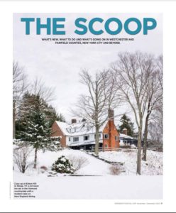 A large white house with dark trim sits among bare trees in a snowy winter landscape. Reminiscent of an Inn Style in Vermont, the yard and roof are blanketed in snow, while an overcast sky creates a peaceful, serene scene.