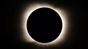 A total solar eclipse with the moon completely covering the sun, revealing the sun’s bright corona as a glowing halo around the dark silhouette of the moon—an unforgettable sight featured in many eclipse travel packages.