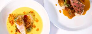 Two elegant plated dishes at this Stowe VT Restaurant: one features fish in a yellow sauce with orange oil and crispy crumble, the other offers sliced meat with brown sauce, Brussels sprouts, and a creamy puree.