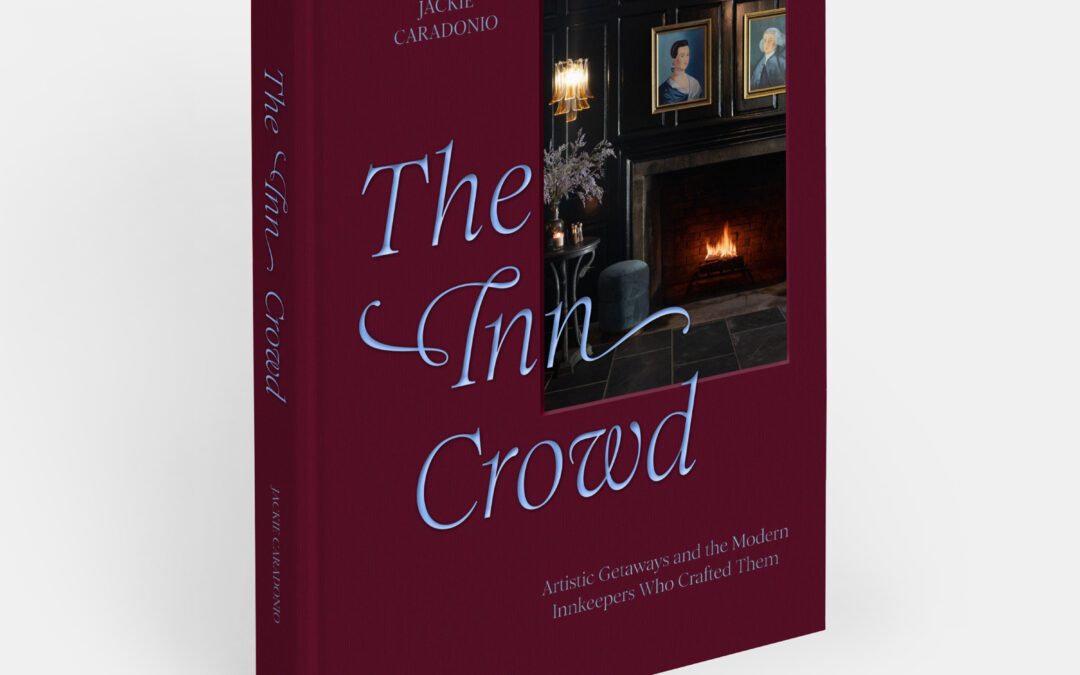 A maroon hardcover book titled The Inn Crowd by Jackie Caradonio. The cover features a framed photo of a cozy room with a fireplace and portraits, evoking the charm of Edson Hill in Vermont in December, along with the subtitle: Artistic Getaways and the Modern Innkeepers Who Crafted Them.