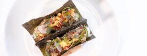 Two seaweed-wrapped tacos filled with a colorful mix of diced vegetables, herbs, and spices, presented on a white plate—a fresh taste reminiscent of the vibrant menus at Edson Hill - Stowe Vermont Inn.